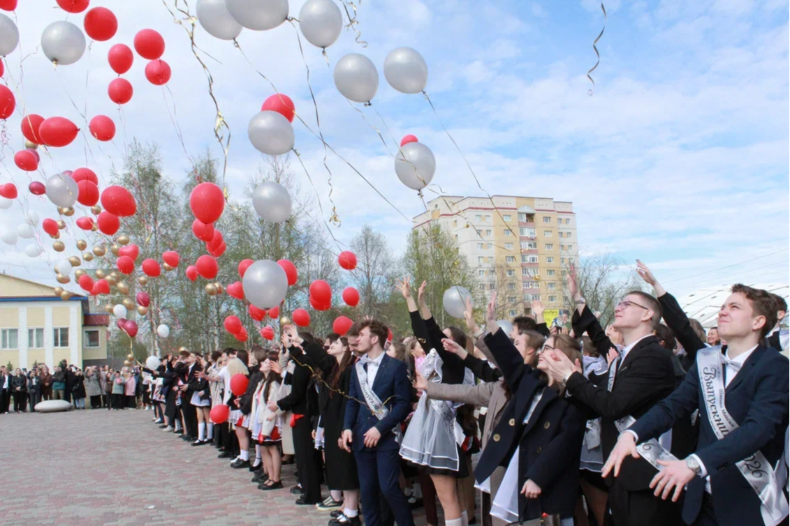 выпускники отпускают воздушные шары в небо.